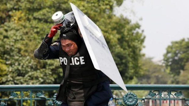 A Thai policeman reacts after an explosion during clashes with anti-government protesters near Government House in Bangkok.