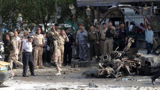 Security forces and civilians inspect the site of a double car bomb attack on Habaybina restaurant in the Shiite-majority district of Talibiya in eastern Baghdad, Iraq.