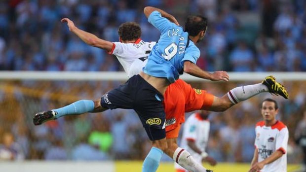 Bruno Cazarine of Sydney FC and Luke Devere of the Roar compete for the ball.