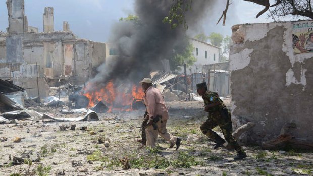 Somali police run for cover after the attack on the main court complex in Mogadishu.