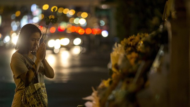 A woman holds up a flower as she prays at the Erawan shrine, the site of a deadly blast, in central Bangkok last year.