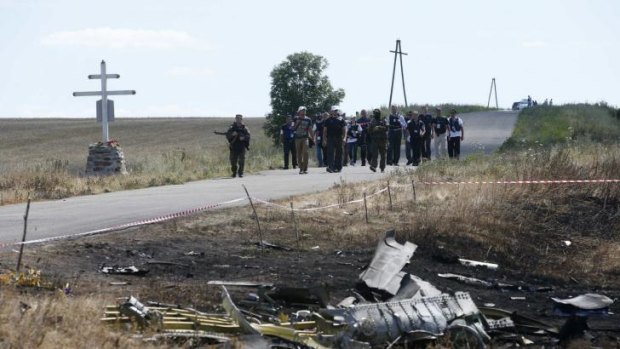 Monitors from the Organisation for Security and Cooperation in Europe and members of a forensic team visit the crash site of Malaysia Airlines Flight on Monday.
