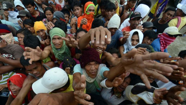 Victims of Typhoon Bopha jostle for position as they beg for relief food being distributed by members of a private company in New Bataan.
