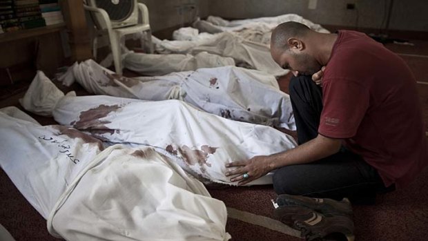 An Egyptian man mourns over a body wrapped in shrouds at a mosque in Cairo.