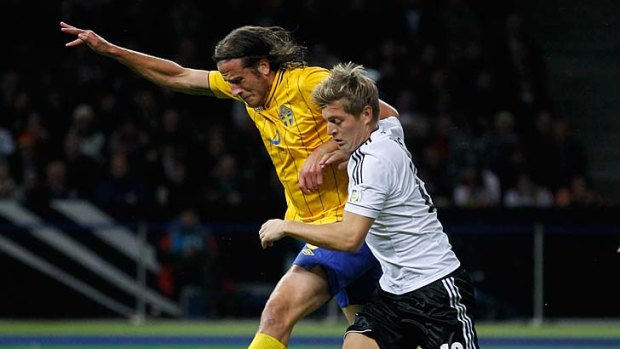 Toni Kroos (right) of Germany and Jonas Olsson of Sweden battle for the ball.