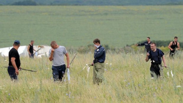 Men search a field in eastern Ukraine for victims of flight MH17.