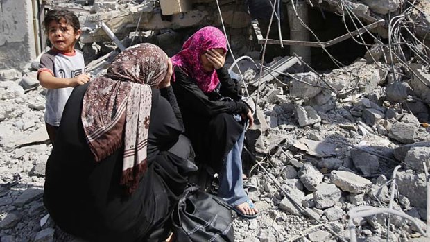 Palestinian women sit on the rubble of their home in Beit Hanoun.