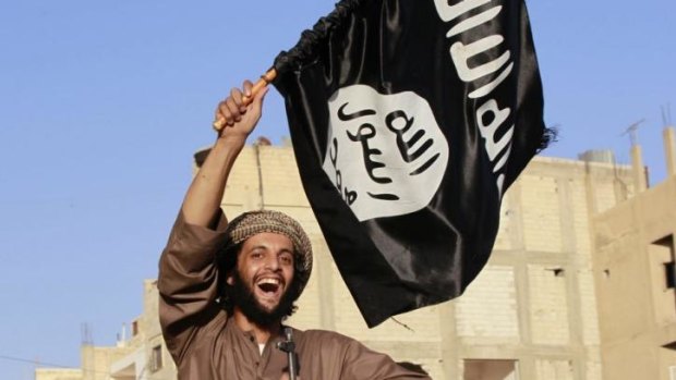 A militant Islamist fighter waving a flag, cheers as he takes part in a military parade along the streets of Syria's northern Raqqa province.