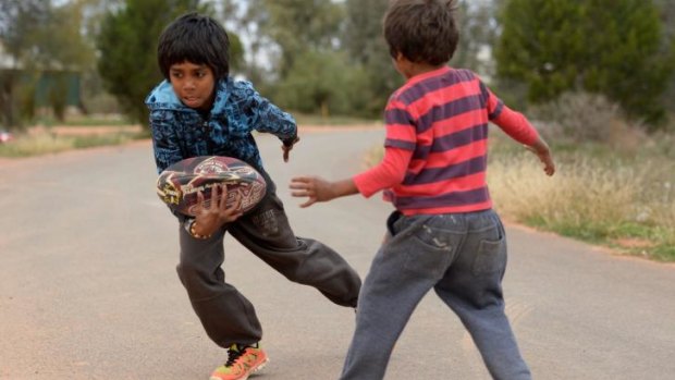 Aboriginal kids in Namatjira Avenue in Dareton near Mildura playing footy on the street.