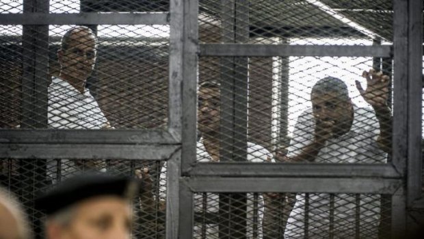 Peter Greste (left) and his colleagues Mohamed Fadel Fahmy and Baher Mohamed listen to the verdict from inside the defendants' cage.