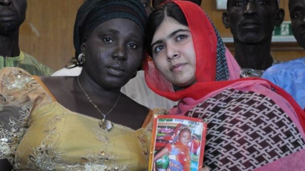 Pakistani activist Malala Yousafzai. who survived being shot by the Taliban. holds a picture of kidnapped schoolgirl Sarah Samuel with her mother Rebecca Samuel, in Abuja, Nigeria.
