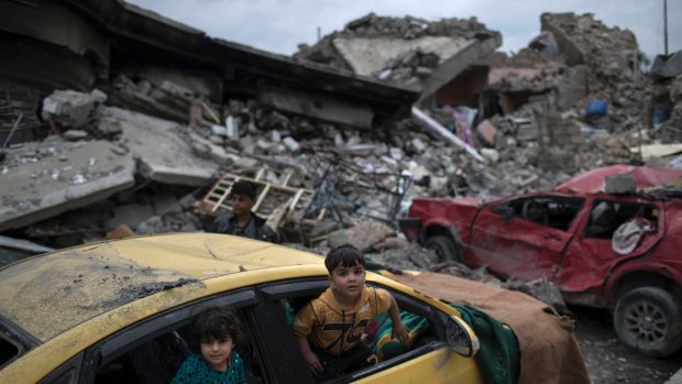 Children play inside a damaged car, amid heavy destruction in a neighborhood recently retaken by Iraqi security forces from Islamic State militants on the western side of Mosul, Iraq.