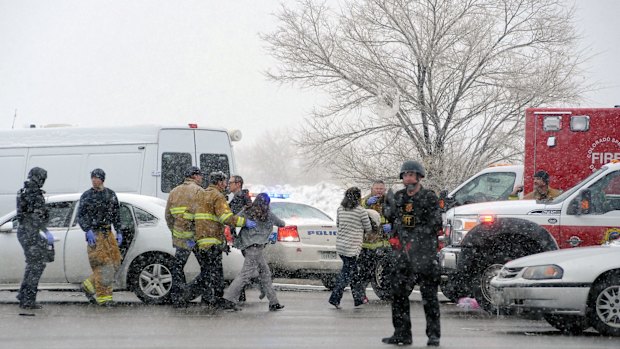 A woman is escorted by emergency workers away from the scene. 