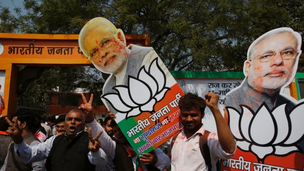 Bharatiya Janata Party supporters raise cutouts of Indian Prime Minister Narendra Modi as they celebrate winning seats in the state of Uttar Pradesh on Saturday.