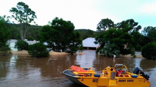 An SES crew rescues a family from a flooded home at Luscombe before it is swept away.