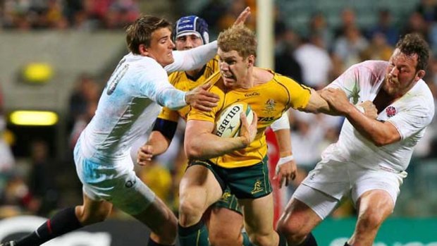 Wallaby David Pocock attempts to barge through the tackling of England?s Toby Flood (left) and Steve Thompson at Subiaco last night.