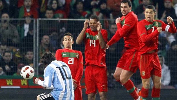 Lionel Messi takes as free kick as Portugal's wall including Cristiano Ronaldo, right, tries to stop it.