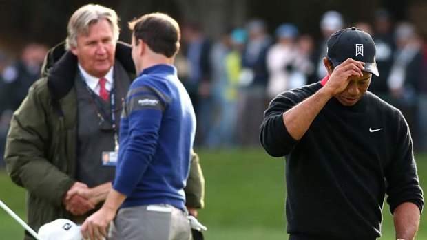 Tigers Woods walks off the green as Zach Johnson is congratulated by PGA Tour rules official Mark Russell.