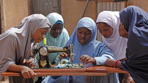 Putting her life back together: Maimuna Abdullahi, centre, speaks to classmates as she sews clothes  at her school.