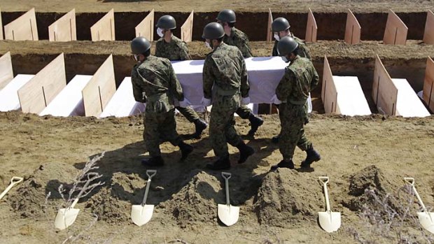 Japanese soldiers bury another victim in a mass grave.