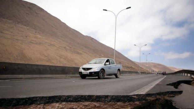 A car stops by a crack on a road damaged by a powerful 8.2-magnitude earthquake that hit off Chile's Pacific coast.