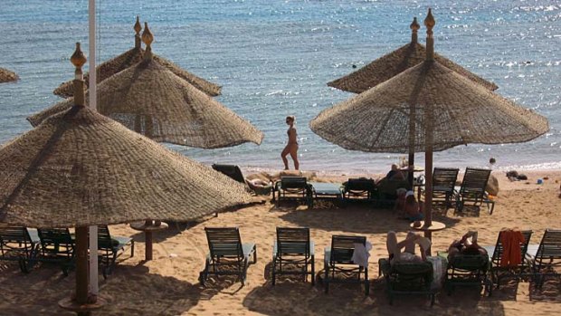 Tourists walk on the beach at the Red Sea in Egypt. Tourism has not recovered after plummeting due to political turmoil.