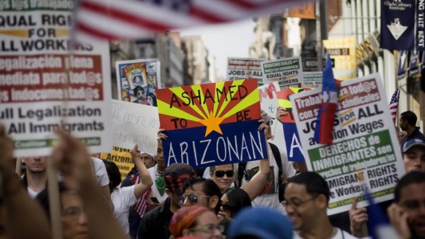 A woman holds a sign reading 'Ashamed to be Arizonan'.