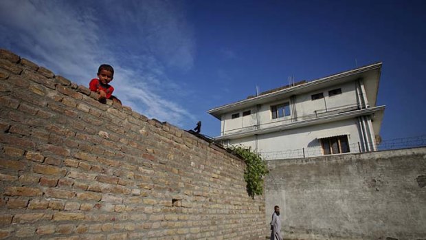 A boy looks over a wall in front of the compound where al Qaeda leader Osama bin Laden was killed in Abbottabad.