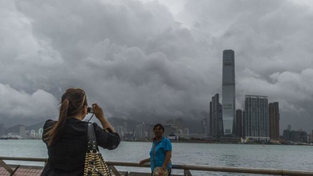 Chinese tourists take pictures in front of the Kowloon skyline during a thunderstorm in Hong Kong caused by Typhoon Kalmaegi on Tuesday.