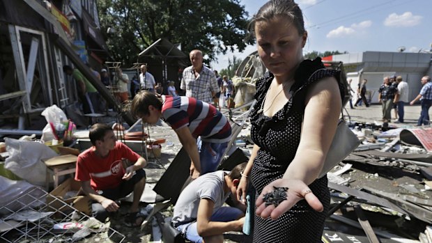 Under siege ... A local woman collects fragments of a shell, after night shelling on a local market, in Donetsk, eastern Ukraine.