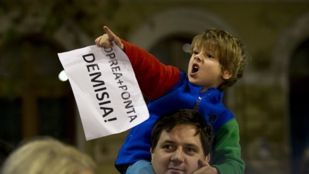 A child holds a piece of paper that reads "Oprea-Ponta-Resignation" during a protest demanding the resignations of Interior Minister Gabriel Oprea and Prime Minister Victor Ponta in Bucharest, Romania, on Monday.