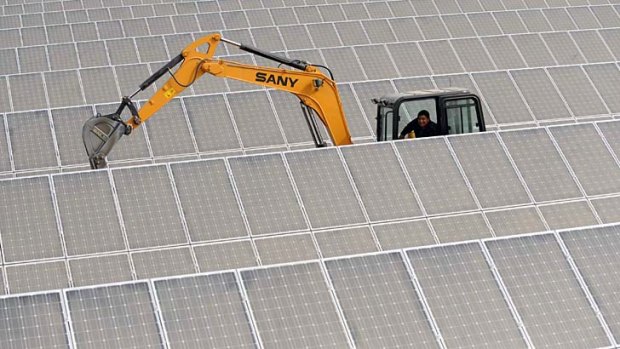 An excavator works among solar panels at a plant in China.