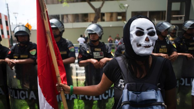 A protester, wearing a skeleton mask, holds a Peruvian national flag during a rally against the Trans-Pacific Partnership in Lima, Peru.