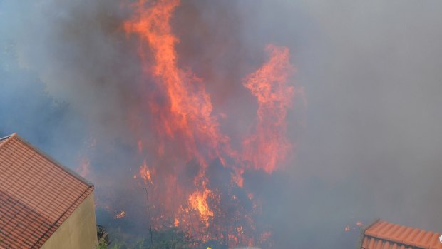 A firefighter works to stop a forest fire from reaching houses on the outskirts of Funchal.