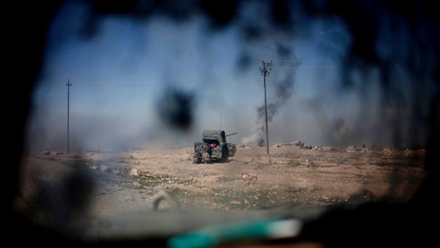 Iraqi police forces fire from a humvee at IS positions from a hillside near Mosul on Monday.