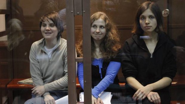 Punished ... Pussy Riot members Yekaterina Samutsevich, Maria Alyokhina and Nadezhda Tolokonnikova sit in a glass-walled cage before their latest  court hearing in Moscow.