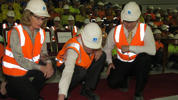 Queensland Governor Penelope Wensley, Lord Mayor Graham Quirk and Councillor Matthew Bourke trowel the top of the time capsule.
