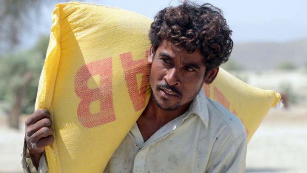 A Pakistani earthquake survivor carries a bag of relief food supplies in Labach, in the earthquake-devastated district of Awaran. Tens of thousands of survivors waited for help in soaring temperatures on Thursday.