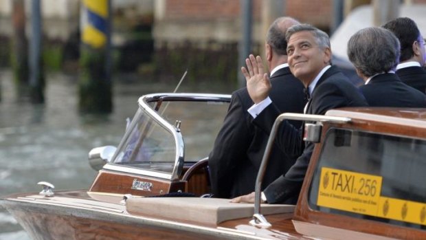 US actor George Clooney waves to fans from a taxi boat.