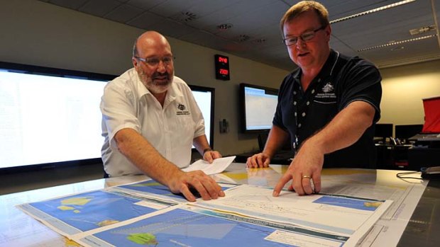Mike Barton, rescue co-ordination chief of the Australian Maritime Safety Authority, left, looks over maps of the Indian Ocean with Alan Lloyd, manager of search and rescue operations. at the Rescue Co-ordination Centre in Canberra