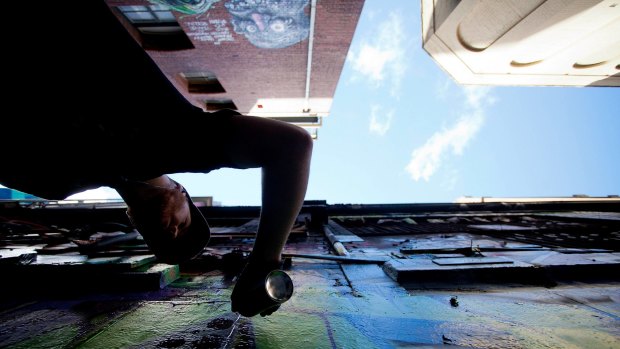 Looking up in Hosier Lane? Graffiti artist The Kromster paints on the wall of the building to be demolished.