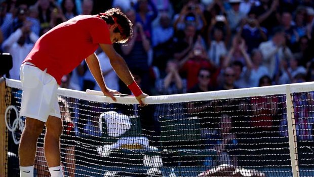 Roger Federer leans on the net after beating Juan Martin del Potro.