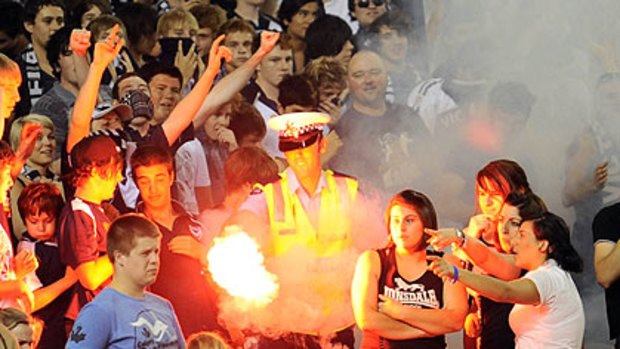 A police officer removes a lit flare at a match between Melbourne Victory and Perth Glory last year.