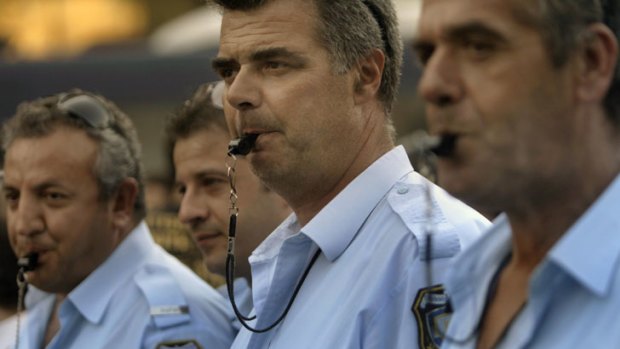 Police officers in Athens blow their whistles to protest against a new austerity package.
