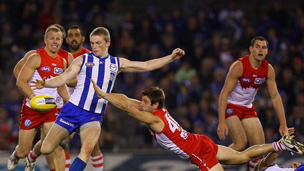North Melbourne's Jack Ziebell gets a kick away despite pressure from Sydney players.