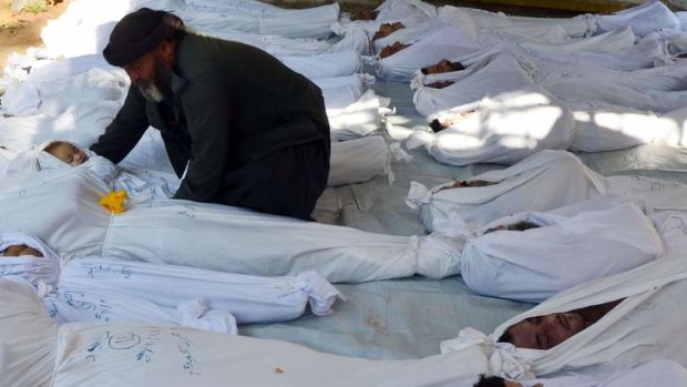 A man holds the body of a dead child among bodies of people activists say were killed by nerve gas in the Ghouta region, in the Duma neighbourhood of Damascus on August 21.