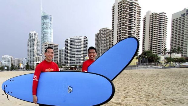 Canadian tourists Clemens Kim and Jordan Chang from Toronto, take in the sights, sun and surf on the Gold Coast.