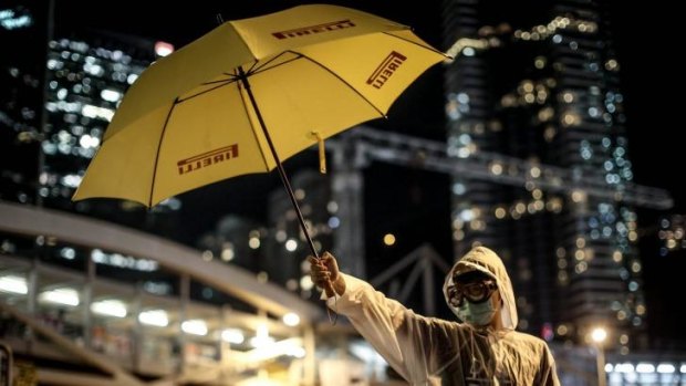 A pro-democracy activists stands with a yellow umbrella