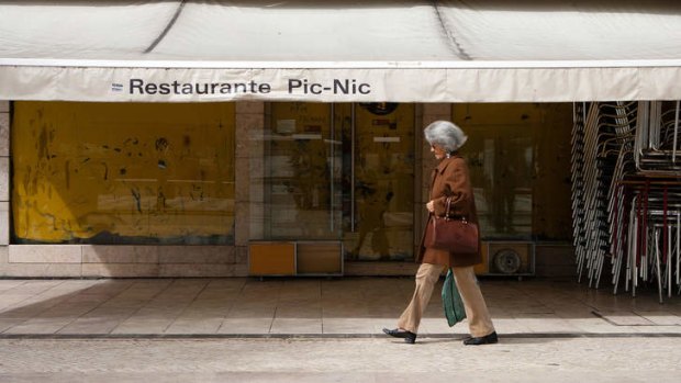 Misery in most of the OECD ... a pedestrian passes a closed down restaurant in Lisbon, where austerity cuts are hurting.