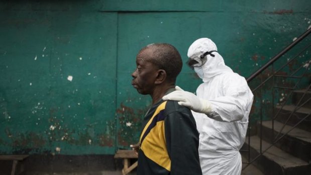 A member of an ambulance team walks a man who is suspected to be infected with Ebola to an ambulance to be taken to an Ebola Treatment Unit.